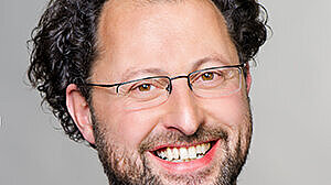 Headshot of Prof. Dr. Johannes Sauere , a middle age man smiling on a simple grey background.