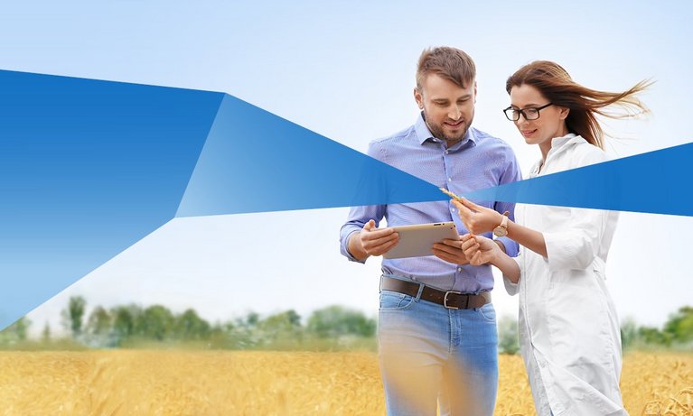 One male and female student in a grain field with tablet