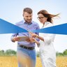 One male and female student in a grain field with tablet