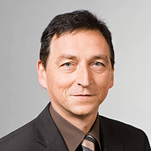 Headshot of Prof. Dr.Rudi Zagst, a middle age man smiling on a simple grey background.